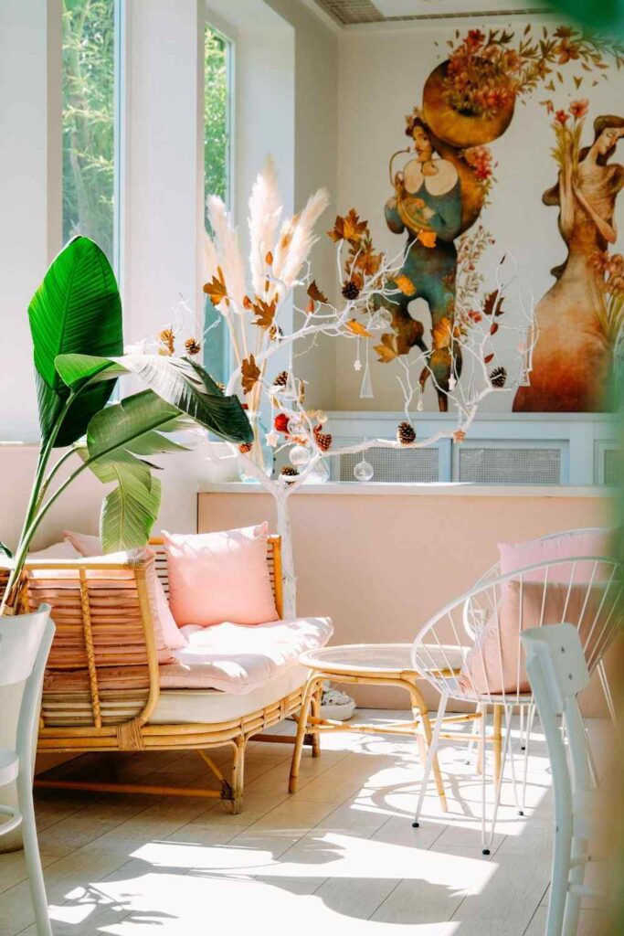 Bright coastal small apartment living room with rattan furniture, blush pink cushions, large windows, and airy neutral decor.