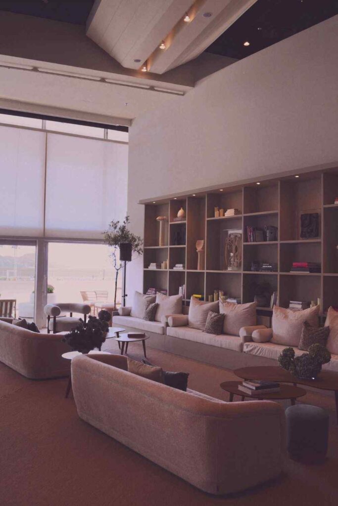 Modern neutral coastal-style living room with curved sofas, warm lighting, and elegant minimalist apartment decor