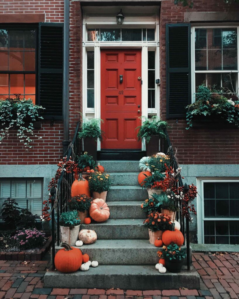 Farmhouse staircase lined with pumpkins, lanterns and seasonal autumn flowers.