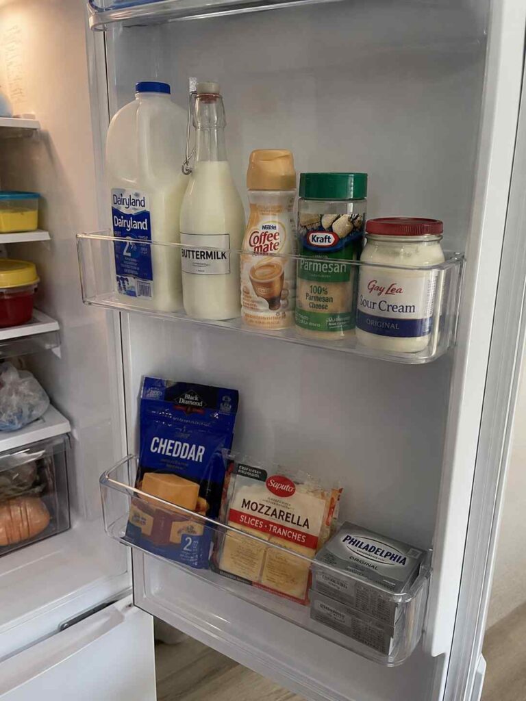 15 Smart Fridge Organization Ideas That Save Space and Reduce Food Waste 9 Refrigerator door organized with milk, yogurt, buttermilk, cheese, and dairy products grouped together in a dedicated dairy section.