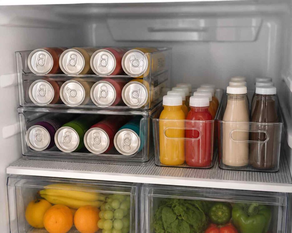 15 Smart Fridge Organization Ideas That Save Space and Reduce Food Waste 5 Dedicated beverage station in a refrigerator with stackable can organizer, juice bottles, protein drinks, and neatly organized beverages.