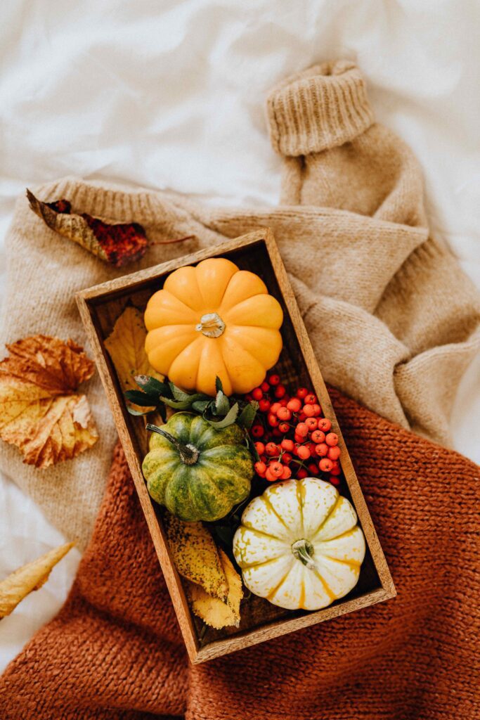 Wooden tray decorated with pumpkins, candles and fall accents on a cozy bedroom bench