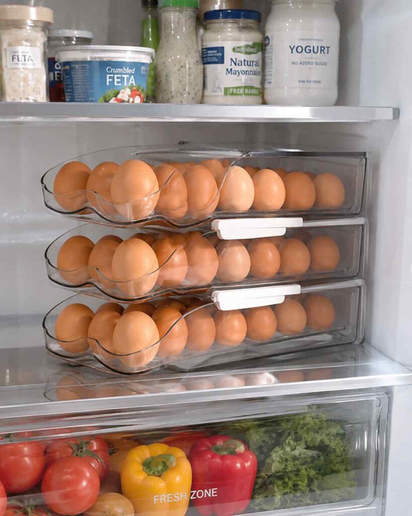15 Smart Fridge Organization Ideas That Save Space and Reduce Food Waste 3 Refrigerator shelf organized with stackable rolling egg holders storing fresh eggs neatly and saving refrigerator space.